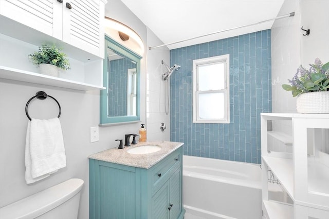 full bathroom featuring vanity, tiled shower / bath, and toilet