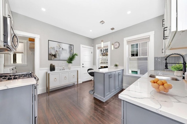 kitchen with sink, gray cabinetry, hanging light fixtures, light stone counters, and stainless steel appliances