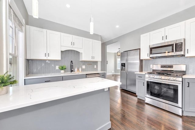 kitchen with white cabinetry, stainless steel appliances, light stone countertops, and hanging light fixtures