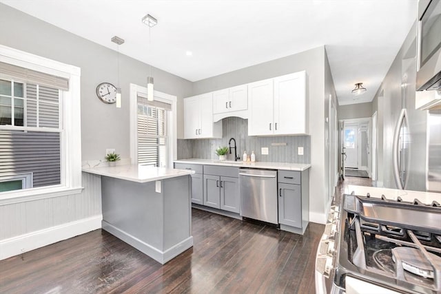 kitchen featuring gray cabinets, kitchen peninsula, pendant lighting, stainless steel appliances, and white cabinets