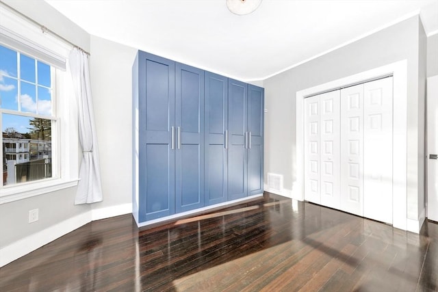 bedroom with dark hardwood / wood-style flooring and a closet