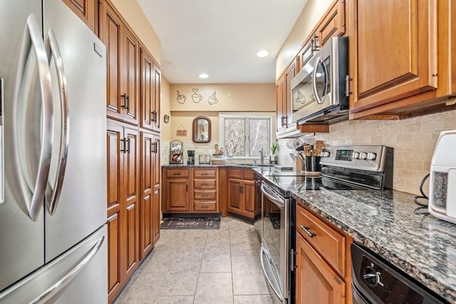 400 N Woodstock Rd, Southbridge, MA 01550 - kitchen with dark stone countertops, appliances with stainless steel finishes, brown cabinets, recessed lighting, and decorative backsplash