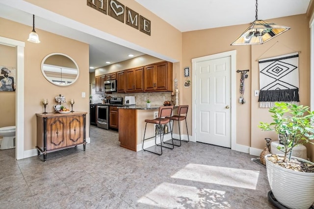 400 N Woodstock Rd, Southbridge, MA 01550 - kitchen featuring hanging light fixtures, backsplash, appliances with stainless steel finishes, and a peninsula