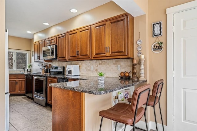 400 N Woodstock Rd, Southbridge, MA 01550 - kitchen featuring tasteful backsplash, brown cabinetry, a peninsula, and stainless steel appliances