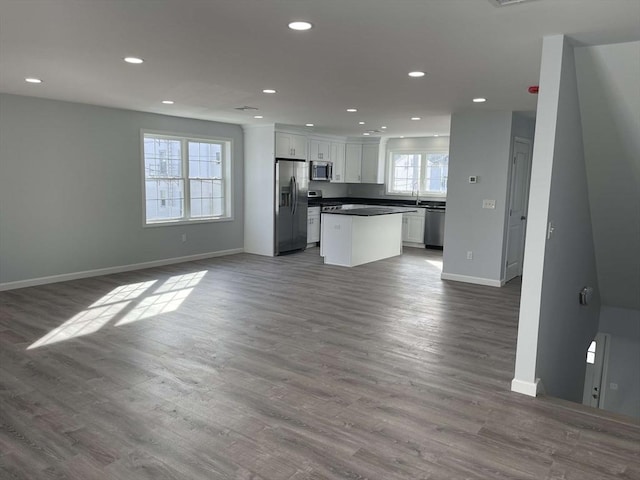 kitchen with white cabinetry, sink, stainless steel appliances, hardwood / wood-style floors, and a kitchen island