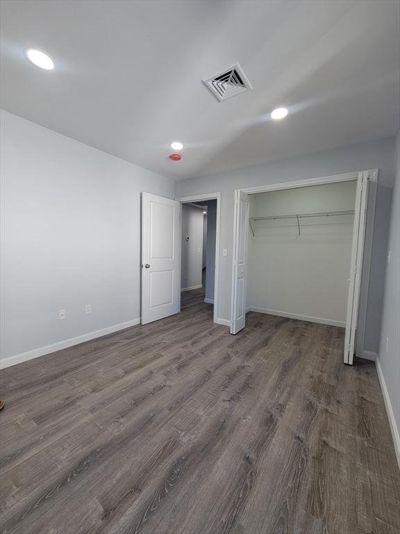 unfurnished bedroom with dark hardwood / wood-style flooring and a closet