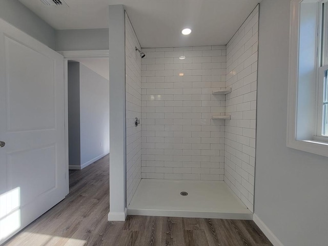 bathroom featuring tiled shower and wood-type flooring