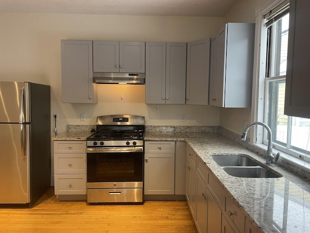 kitchen featuring appliances with stainless steel finishes, light stone counters, gray cabinetry, and sink