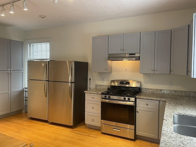 kitchen featuring gray cabinetry, light stone counters, light hardwood / wood-style flooring, and appliances with stainless steel finishes