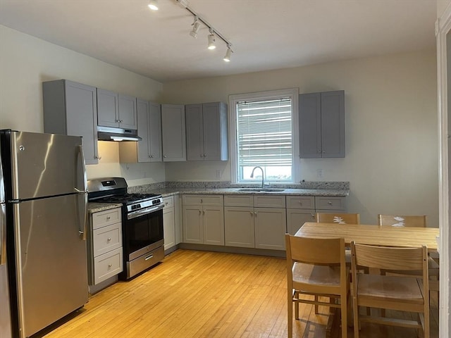 kitchen featuring stainless steel appliances, light stone counters, gray cabinetry, and sink