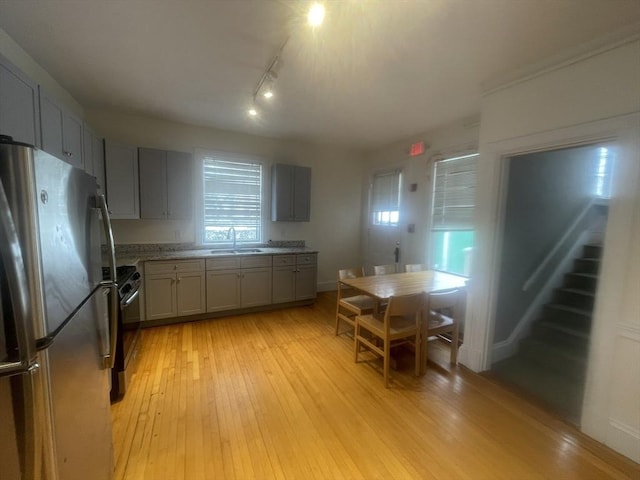 kitchen with gray cabinetry, sink, stainless steel appliances, light hardwood / wood-style flooring, and track lighting