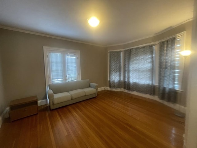 unfurnished living room featuring wood-type flooring and crown molding