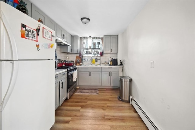 90 Montaup St, Fall River, MA 02724 - kitchen featuring freestanding refrigerator, stainless steel gas stove, gray cabinetry, under cabinet range hood, and tasteful backsplash