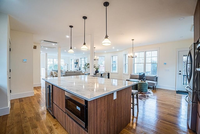 kitchen with baseboards, open floor plan, appliances with stainless steel finishes, and wood finished floors