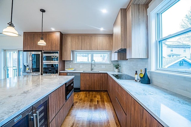 kitchen with a sink, dark wood finished floors, brown cabinetry, stainless steel appliances, and backsplash