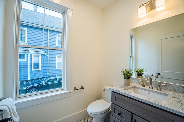 half bathroom featuring toilet, baseboards, and vanity