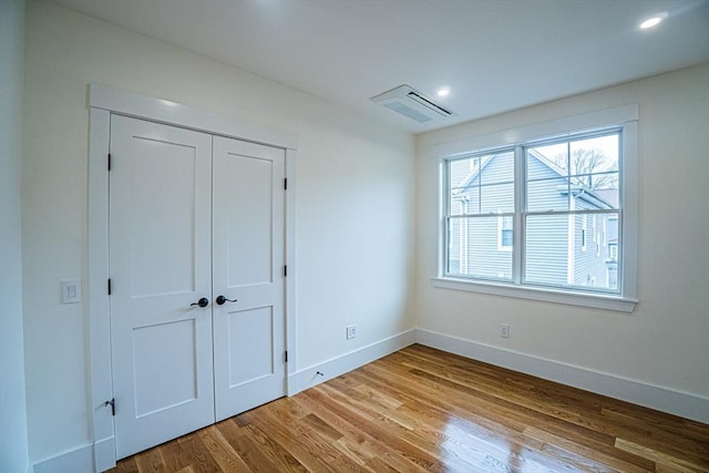 unfurnished bedroom featuring recessed lighting, baseboards, wood finished floors, visible vents, and a closet