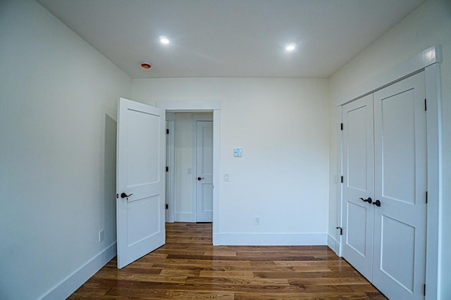 unfurnished bedroom with recessed lighting, baseboards, and dark wood-type flooring