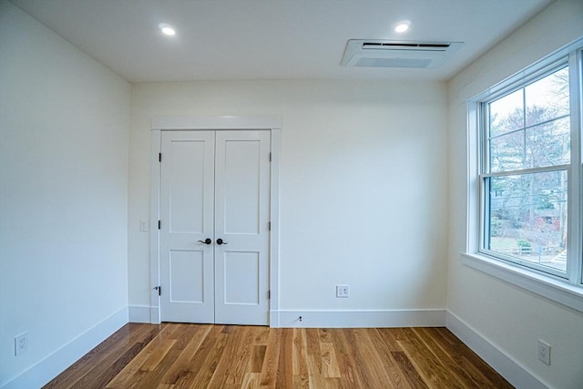 unfurnished room with a healthy amount of sunlight, baseboards, wood finished floors, and visible vents