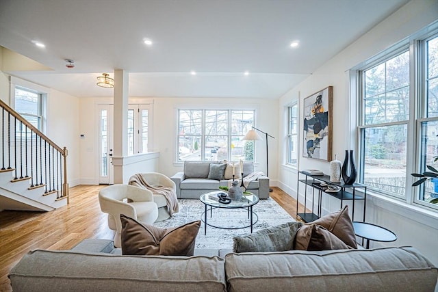 living area featuring stairs, baseboards, and light wood-style flooring