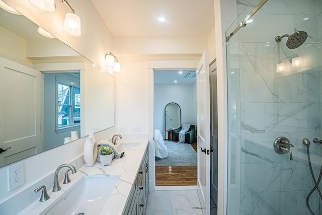 ensuite bathroom with a sink, a marble finish shower, double vanity, and marble finish floor