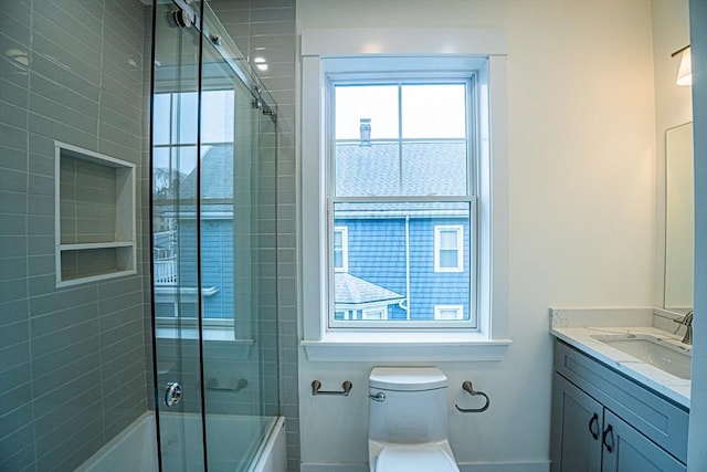 full bath featuring vanity, baseboards, combined bath / shower with glass door, and toilet