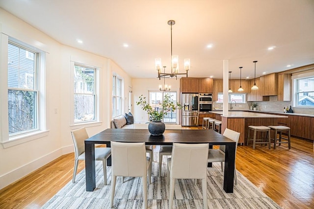dining room with light wood-style floors, recessed lighting, baseboards, and a notable chandelier