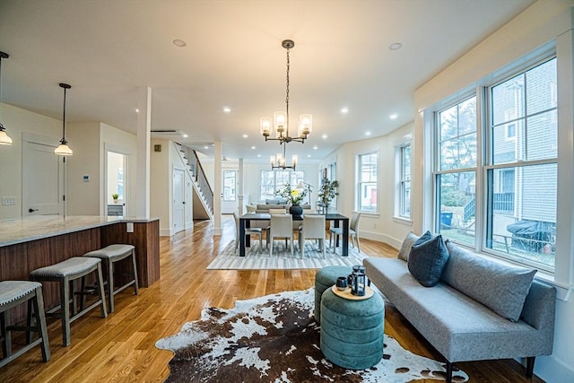 living room with stairs, baseboards, light wood-type flooring, recessed lighting, and a notable chandelier