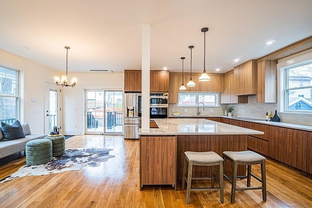 kitchen featuring a kitchen island, brown cabinetry, a sink, and double oven