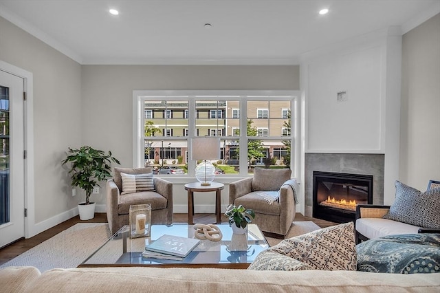 living area featuring crown molding, a glass covered fireplace, wood finished floors, and recessed lighting