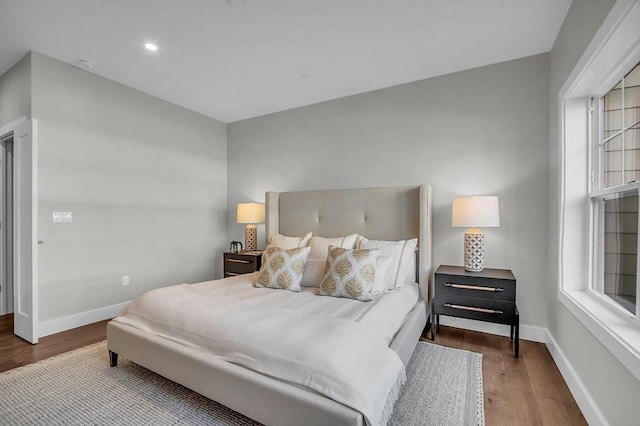 bedroom with recessed lighting, wood finished floors, baseboards, and multiple windows