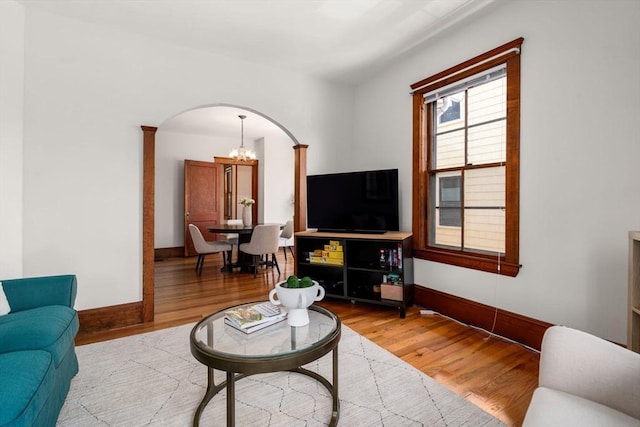 living room with arched walkways, baseboards, wood finished floors, and a chandelier