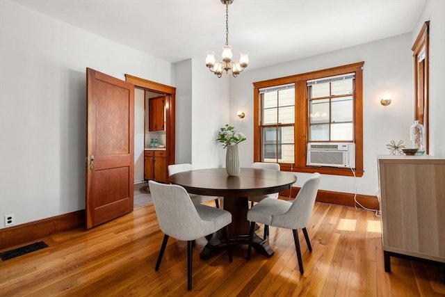 dining space with visible vents, light wood-type flooring, baseboards, cooling unit, and an inviting chandelier