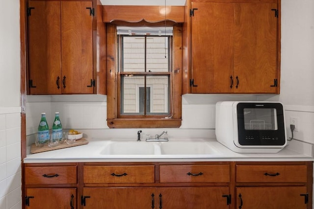 kitchen featuring a sink, light countertops, and brown cabinetry