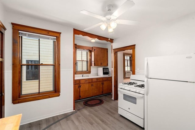 kitchen featuring brown cabinetry, light countertops, light wood-style flooring, and white appliances