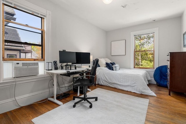 bedroom with cooling unit and wood finished floors