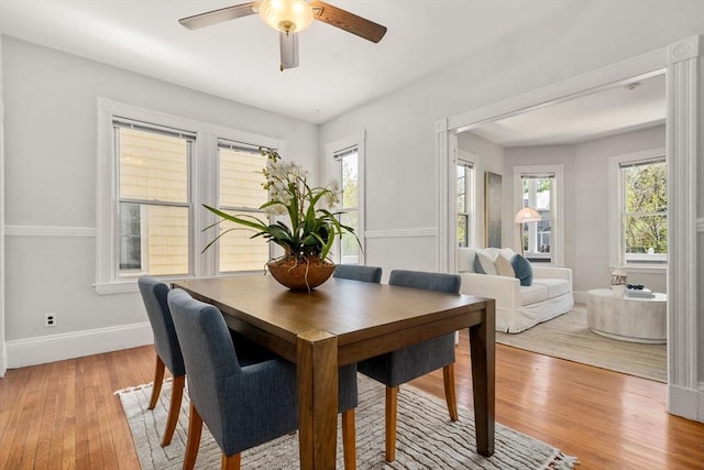 dining room featuring light wood-type flooring, a ceiling fan, and baseboards