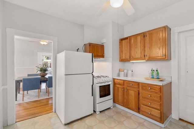 kitchen featuring ceiling fan, white appliances, light countertops, brown cabinetry, and light floors