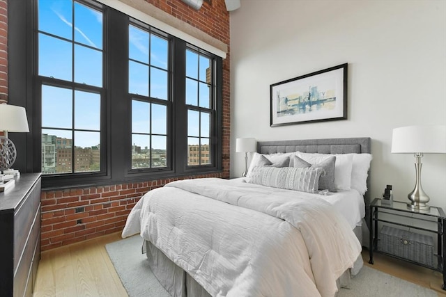 bedroom with brick wall and wood finished floors