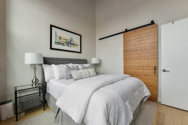 bedroom featuring a barn door and wood finished floors