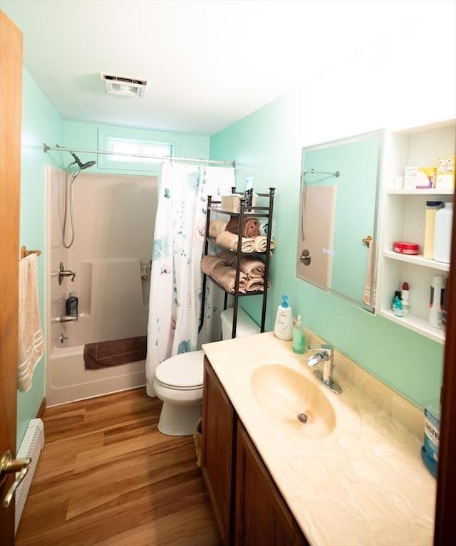 bathroom with vanity, toilet, shower / bathtub combination with curtain, wood finished floors, and visible vents