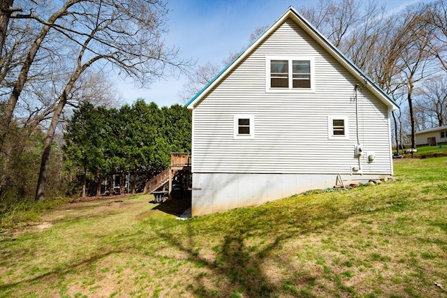 view of side of property featuring a lawn and stairs