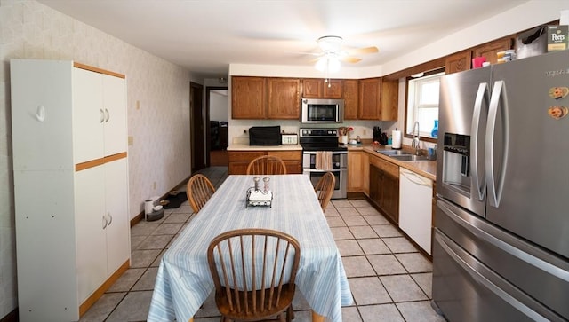 kitchen featuring ceiling fan, wallpapered walls, a sink, appliances with stainless steel finishes, and light tile patterned floors