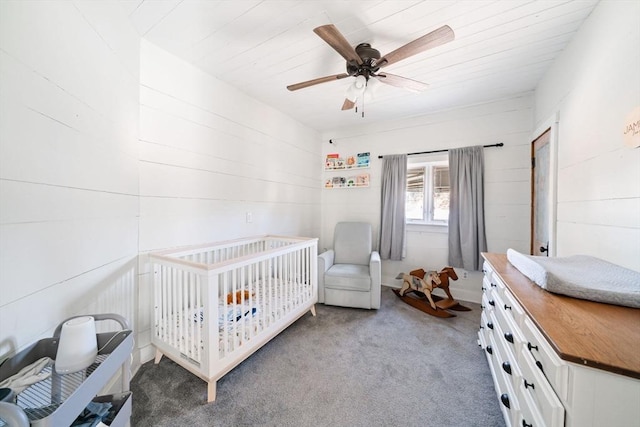 carpeted bedroom with ceiling fan and a nursery area