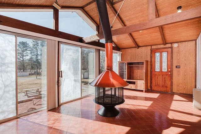 foyer entrance with a wood stove, tile patterned flooring, wood ceiling, wood walls, and beamed ceiling