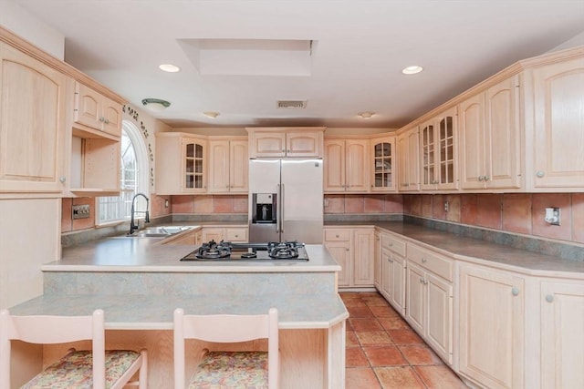 kitchen featuring glass insert cabinets, stainless steel fridge with ice dispenser, a breakfast bar, black gas cooktop, and a peninsula