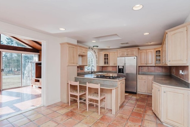 kitchen with a wealth of natural light, recessed lighting, glass insert cabinets, and stainless steel refrigerator with ice dispenser