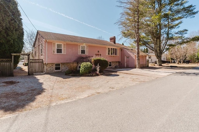 split foyer home with fence and a chimney