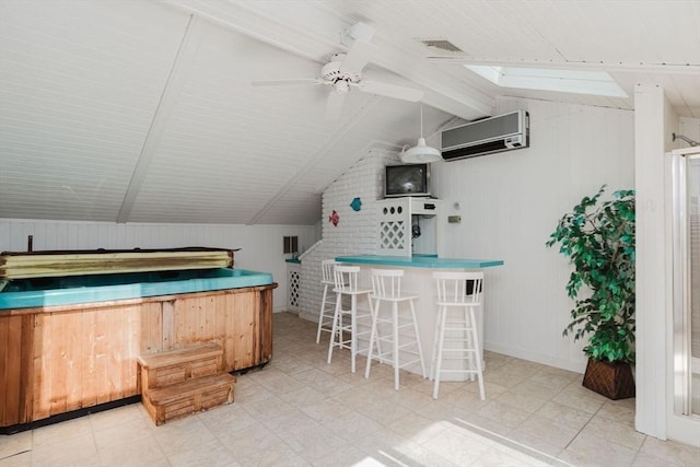 bar featuring visible vents, vaulted ceiling with skylight, a wall mounted AC, and ceiling fan