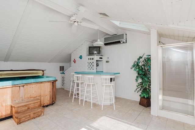 interior space with visible vents, ceiling fan, a breakfast bar, a wall mounted air conditioner, and vaulted ceiling with skylight